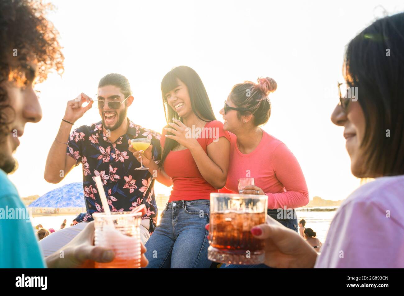 Les amis multiraciaux font des visages fous souriant au bar de la plage tout en buvant un cocktail - concept d'amitié d'été avec les jeunes qui s'amusent ensemble Banque D'Images