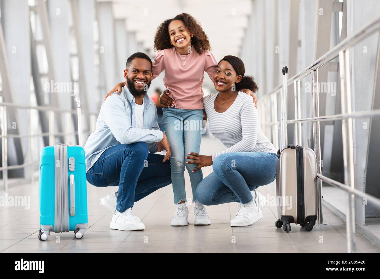 Bonne famille noire excitée voyageant, posant à l'aéroport Banque D'Images