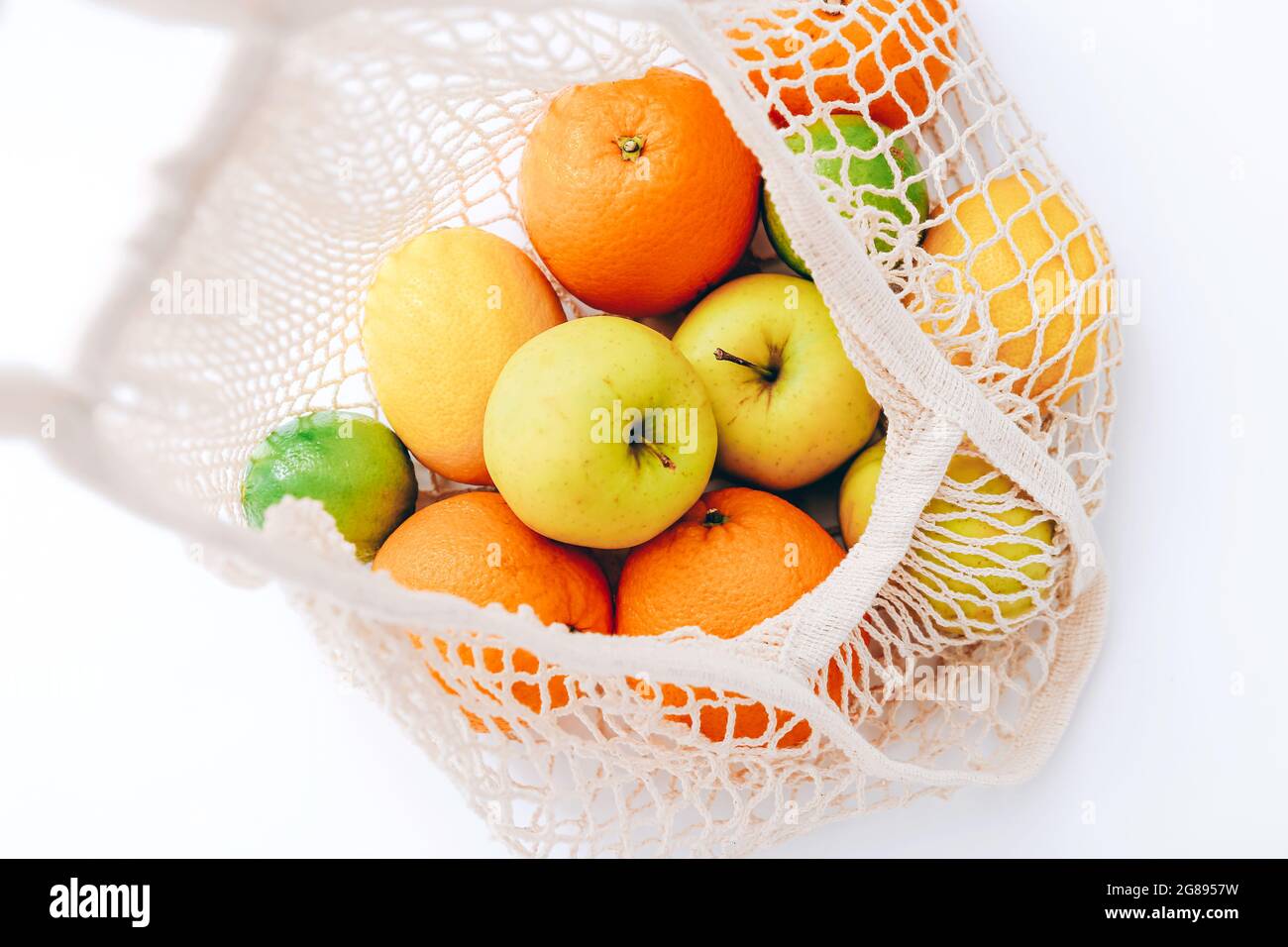Sac à provisions en maille avec fruits frais sur fond clair. Concept sans déchets, sans plastique. Banque D'Images