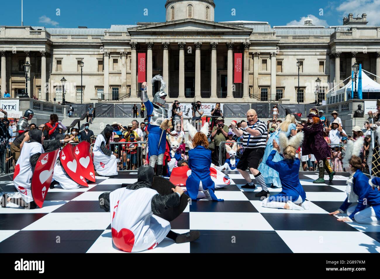 Londres, Royaume-Uni. 18 juillet 2021. Des acteurs costumés prennent part à une partie d'échecs humains à Chess Fest à Trafalgar Square. L'événement célèbre le jeu d'échecs et les visiteurs peuvent apprendre le jeu, jouer aux échecs ou défier un grand maître. De plus, pour célébrer le 150e anniversaire d’Alice de Lewis Carroll à travers le livre look Glass qui présentait le jeu d’échecs, 32 acteurs habillés comme Alice à travers les personnages look Glass se tiennent sur un échiquier géant rejouant un jeu basé sur le livre. Credit: Stephen Chung / Alamy Live News Banque D'Images