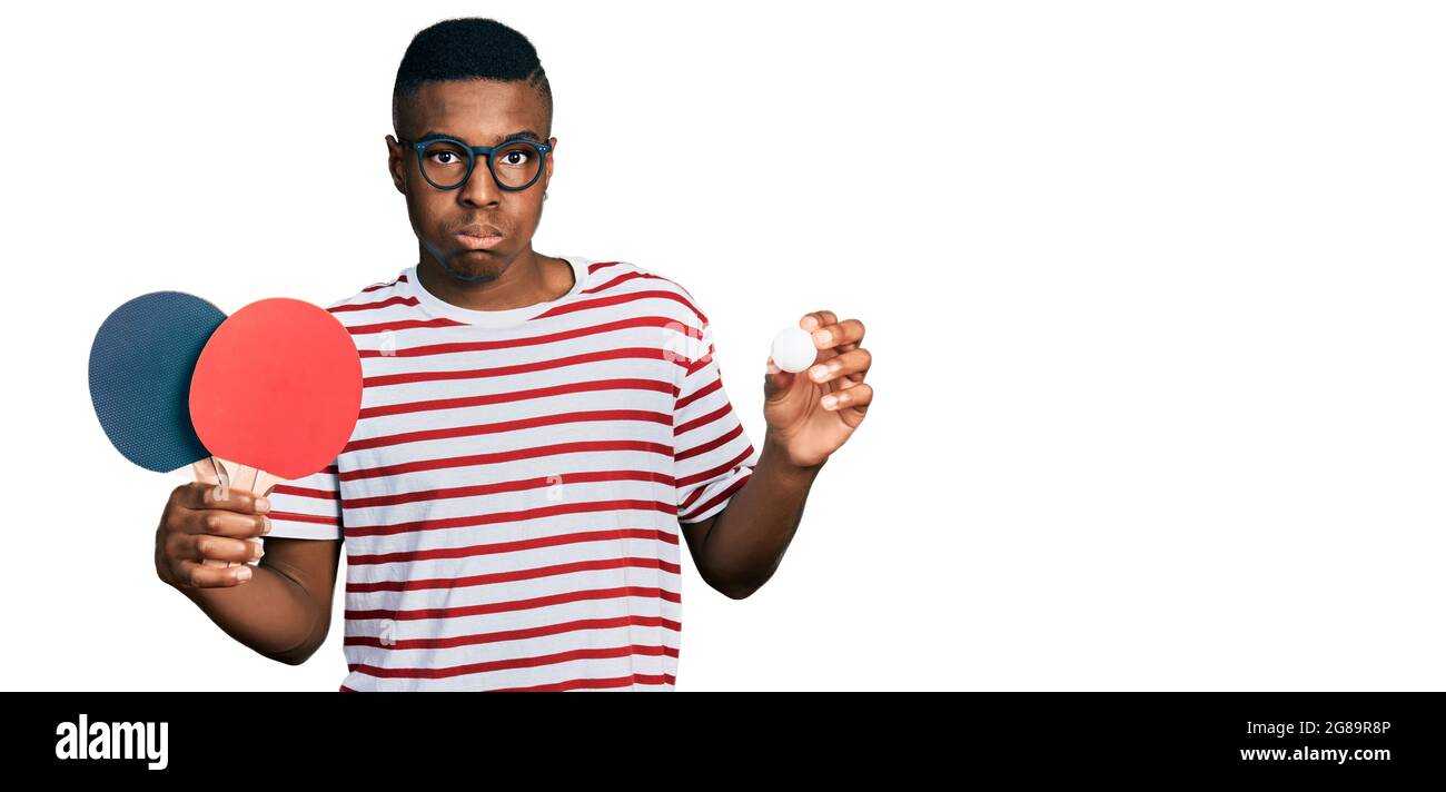 Jeune afro-américain tenant des raquettes de ping-pong rouges et des joues  de bouffrage de balle avec le visage drôle. Bouche gonflée avec l'air,  attrapant l'air Photo Stock - Alamy