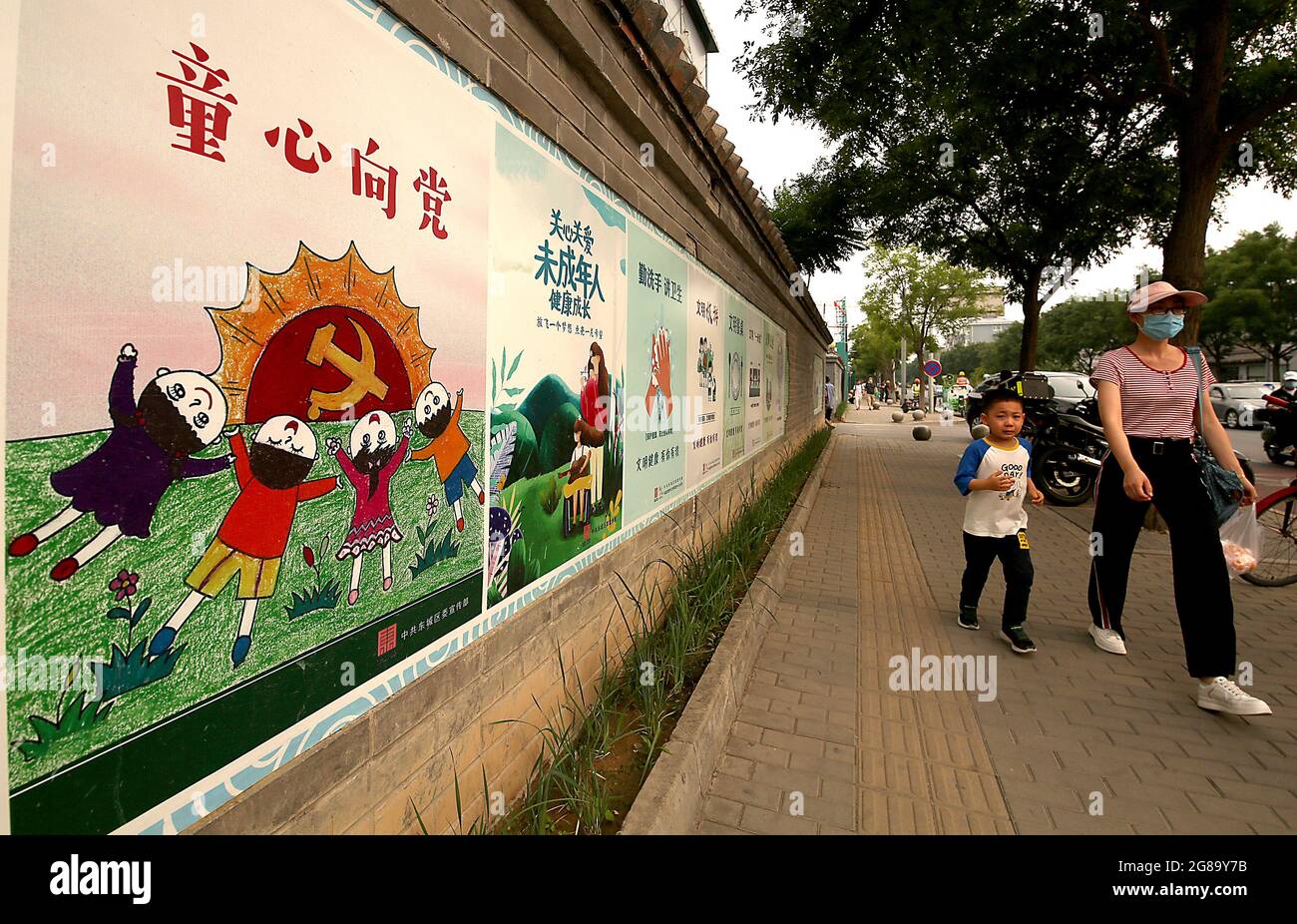 Pékin, Chine. 18 juillet 2021. Les Chinois marchent devant une fresque du Parti communiste vantant les avantages offerts aux enfants par le Parti à Beijing, le dimanche 18 juillet 2021. Les affiches et slogans de style soviétique en Chine ont lancé une campagne de propagande pour promouvoir la nouvelle politique des trois enfants du pays. Photo de Stephen Shaver/UPI crédit: UPI/Alay Live News Banque D'Images
