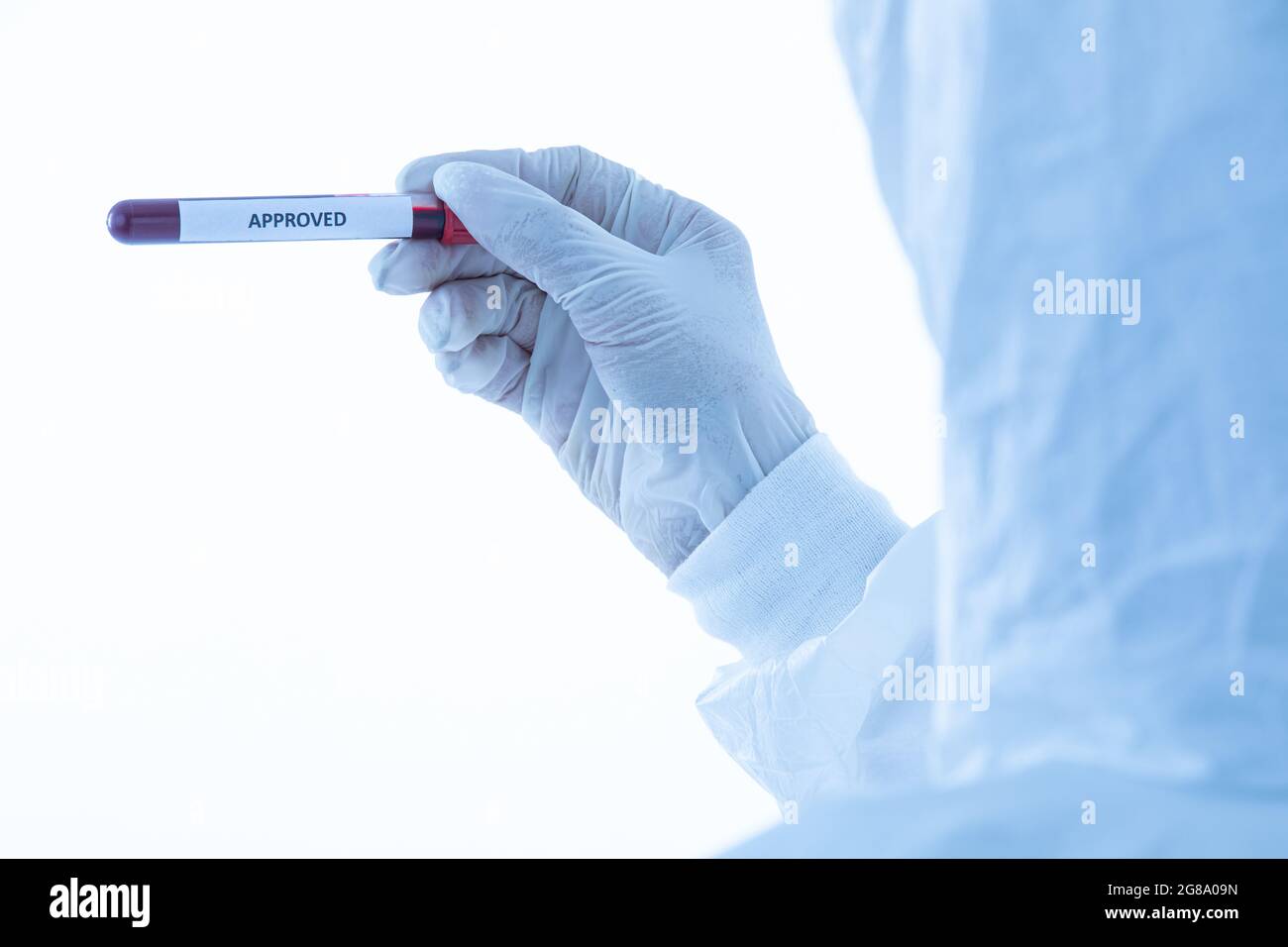 Main du chercheur dans une robe de protection stérilisée tenant le tube à essai approuvé sur un fond blanc isolé. Idée pour les scientifiques travaillent et tentent de réussir Banque D'Images
