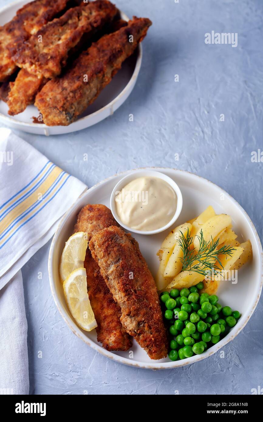 Poisson frit avec des pois verts, du citron et des pommes de terre frites Banque D'Images