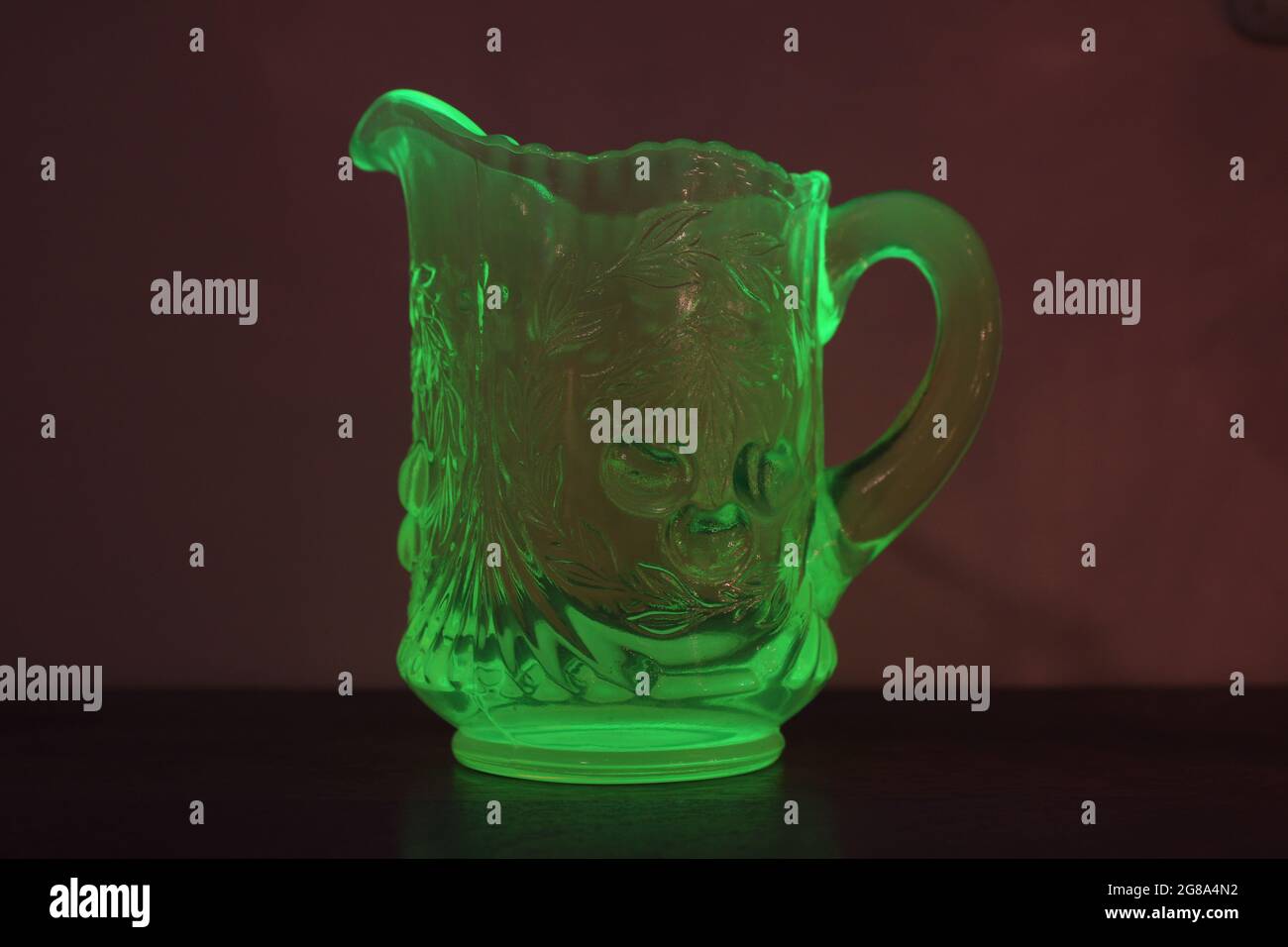 Un crémier en verre d'uranium rétro illuminant sous une lumière noire Banque D'Images
