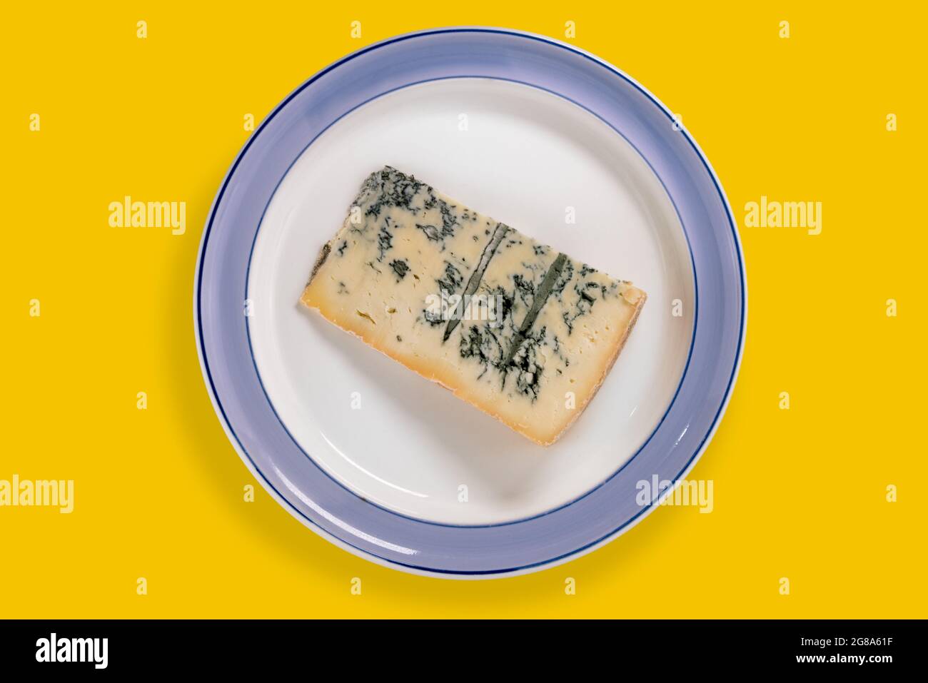 Le gorgonzola italien, une tranche de moule bleu dans une assiette avec bord bleu isolé sur jaune, vue de dessus, plat Banque D'Images