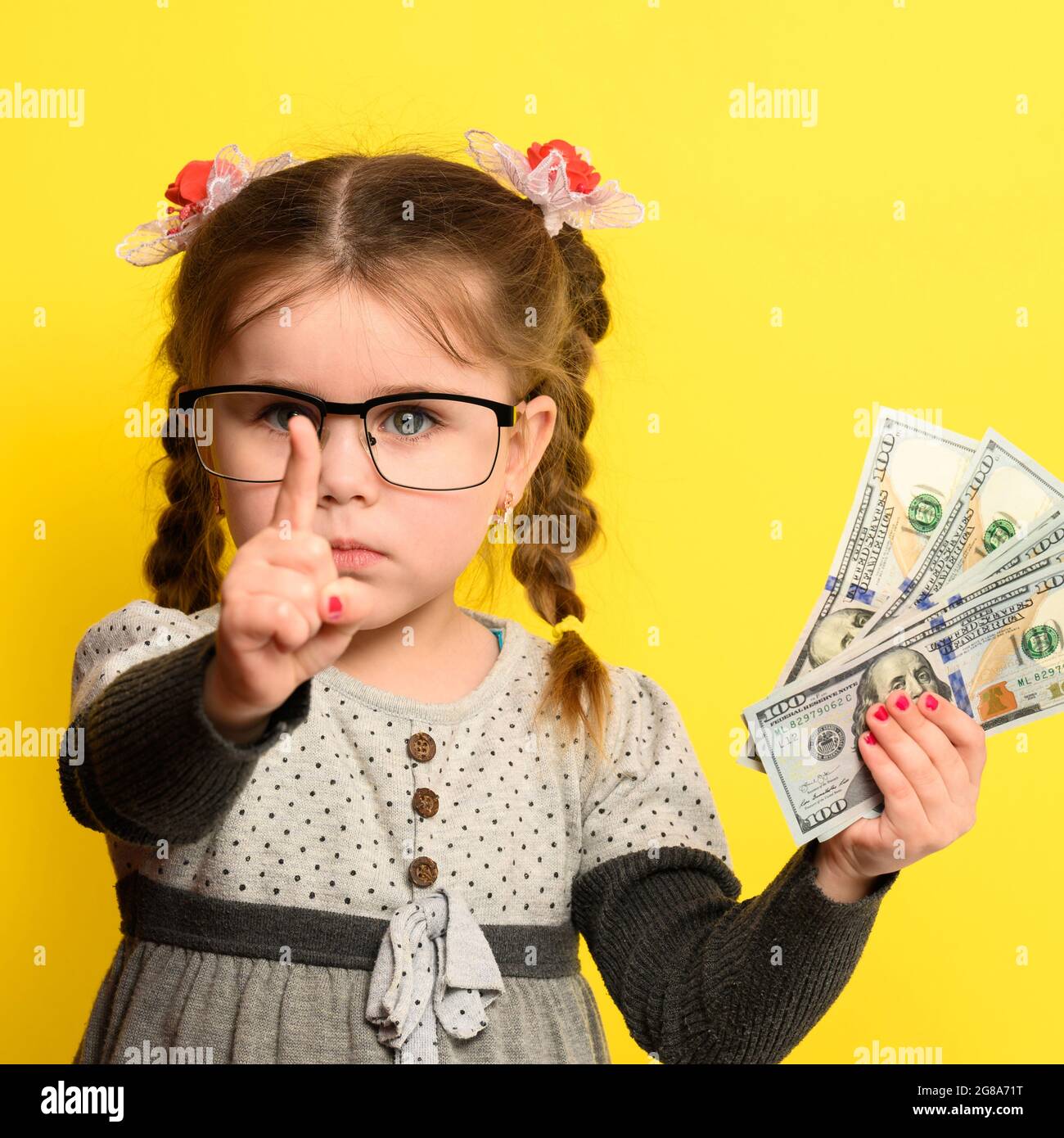 L'argent et les enfants sur le fond, une fille riche avec des verres tenant une grande somme d'argent. Banque D'Images