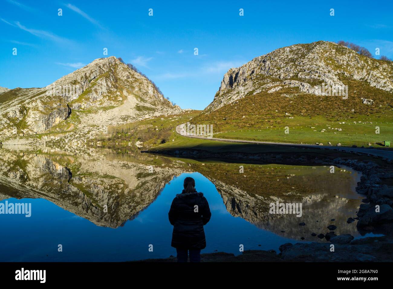 Silhouette d'une femme observant le reflet des montagnes du lac énol. La photo est prise au lever du soleil dans les lacs de Covadonga, Asturies, S. Banque D'Images