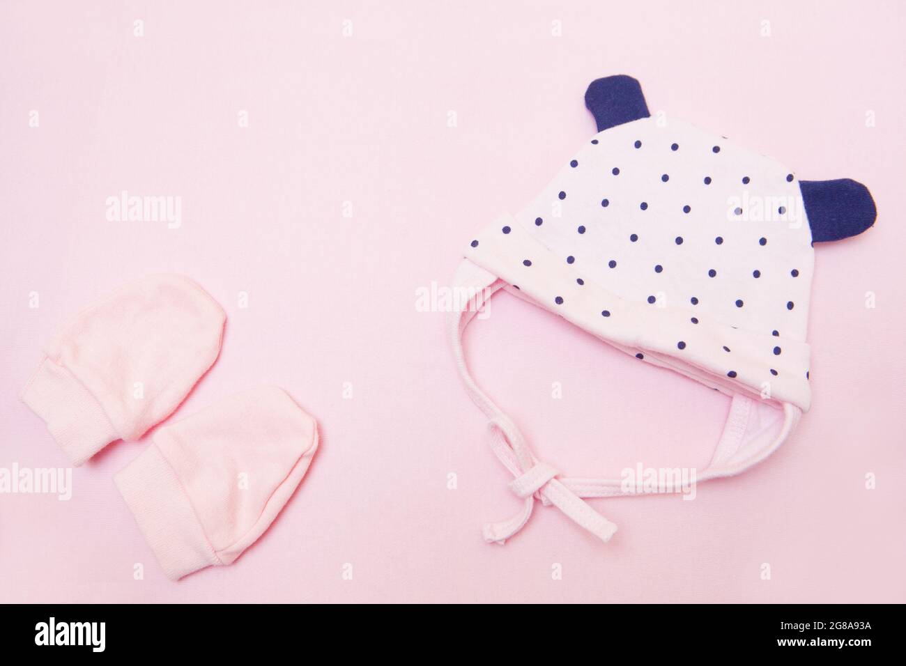 coif et mitaines nouveau-nés roses. Vêtements de fille sur fond rose vue du dessus Banque D'Images