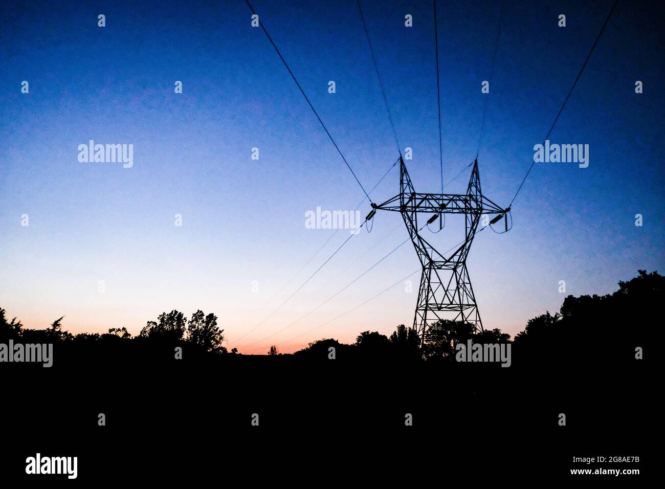 Tours et fils de transmission électriques au coucher du soleil. Banque D'Images