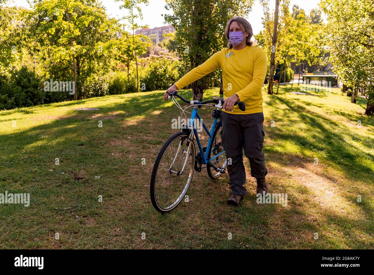 Homme marchant dans le parc avec son vélo Banque D'Images