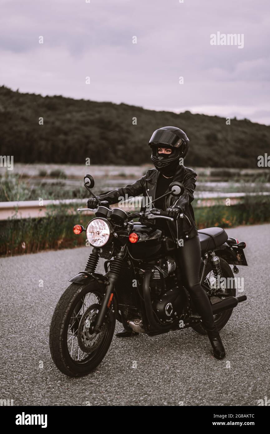 Moto élégante femme en casque et veste en cuir sur moto vintage. Femme  pilote à l'extérieur sur fond de nature. Voyage, courses de café Photo  Stock - Alamy