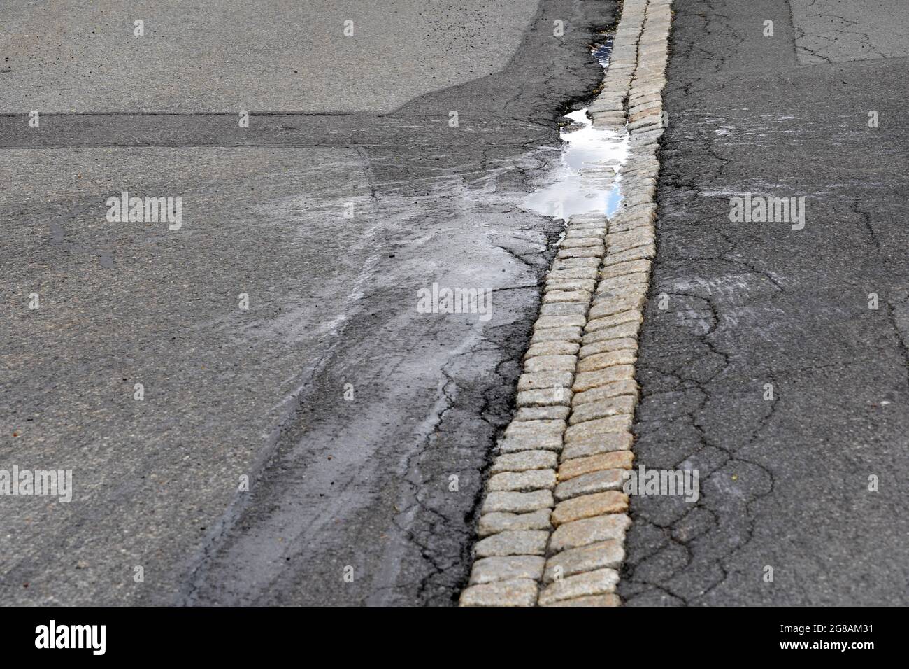 Route avec un pothole. Il y a une flaque d'eau de pluie dans le pothole. L'eau est également éclaboussé. Dans la flaque il y a le reflet de la sk Banque D'Images