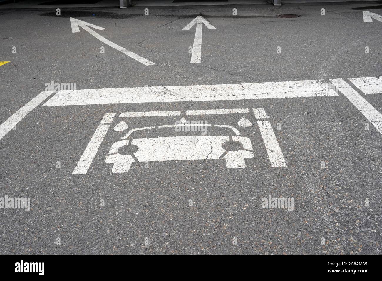 Pictogramme d'une voiture au sol avec deux flèches indiquant la direction de l'installation de lavage de voiture. Vue rapprochée. Les flèches indiquent les cases du libre-service. Banque D'Images