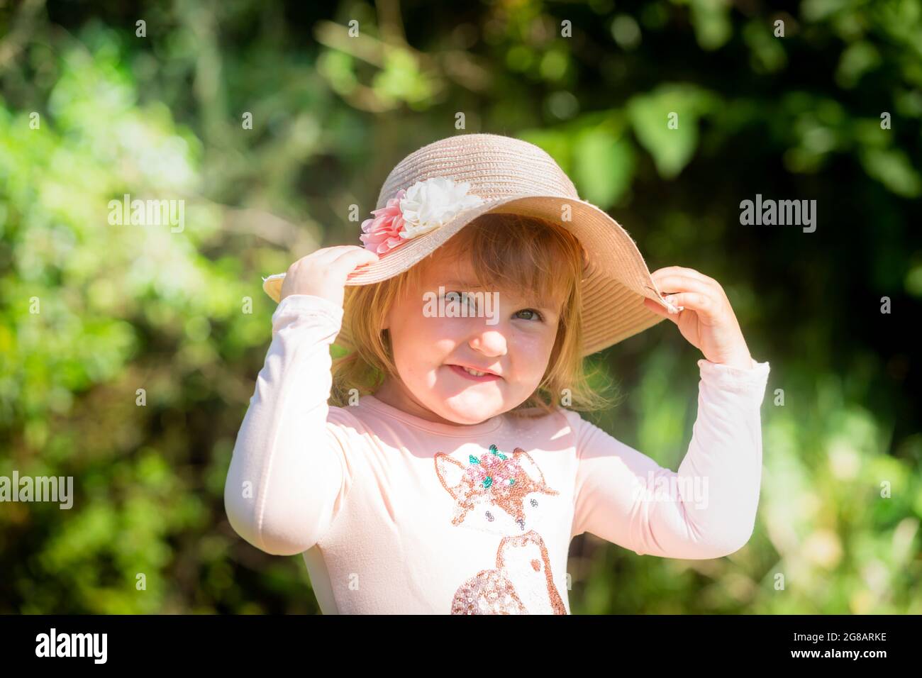 Fille blanche de deux ans, gros plan, portant un chapeau et souriant Banque D'Images