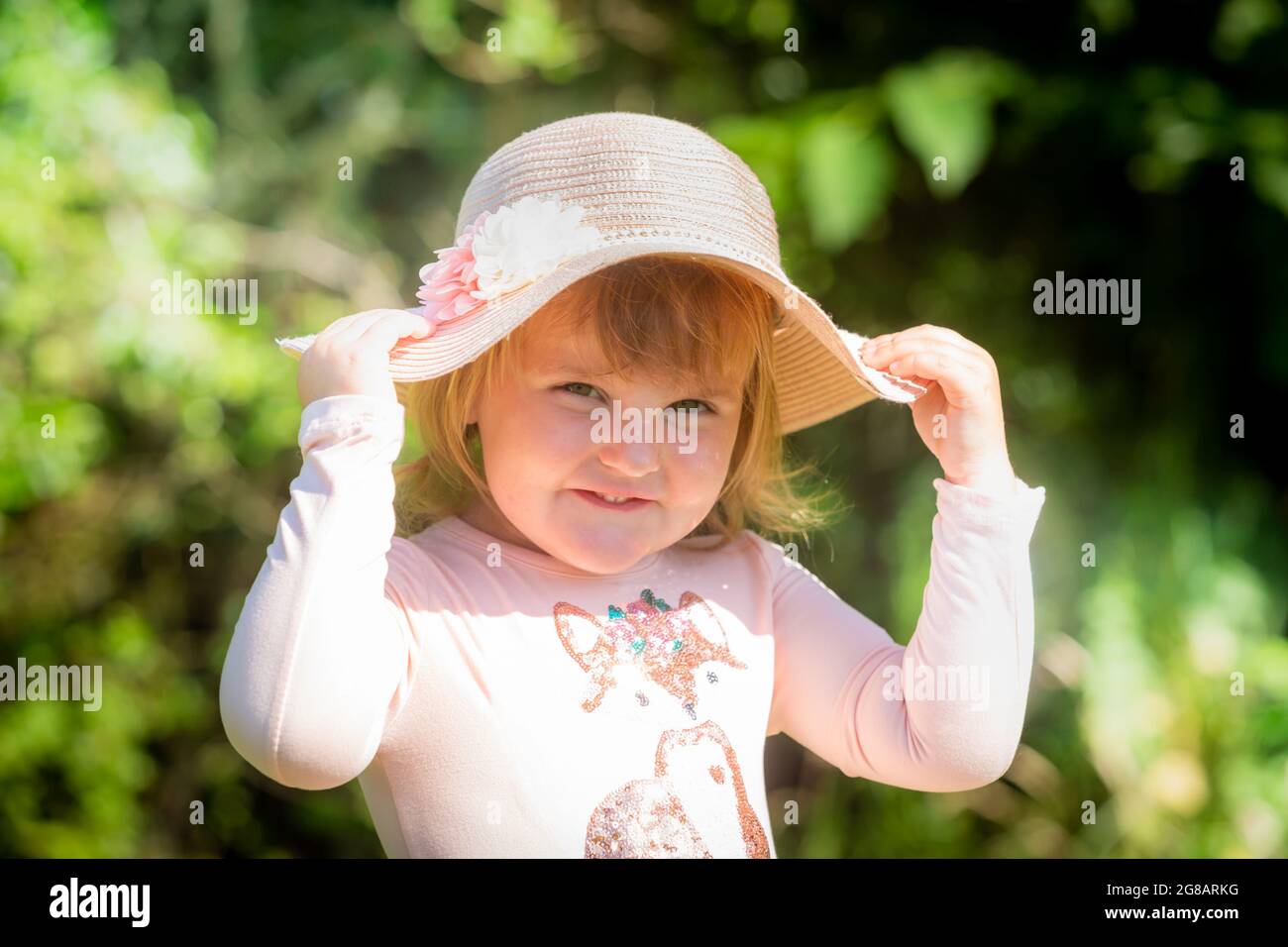 Fille blanche de deux ans, gros plan, portant un chapeau et souriant Banque D'Images