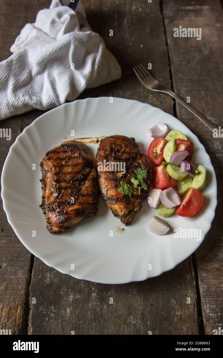 Steak de poulet et légumes dans une assiette blanche sur fond de bois Banque D'Images