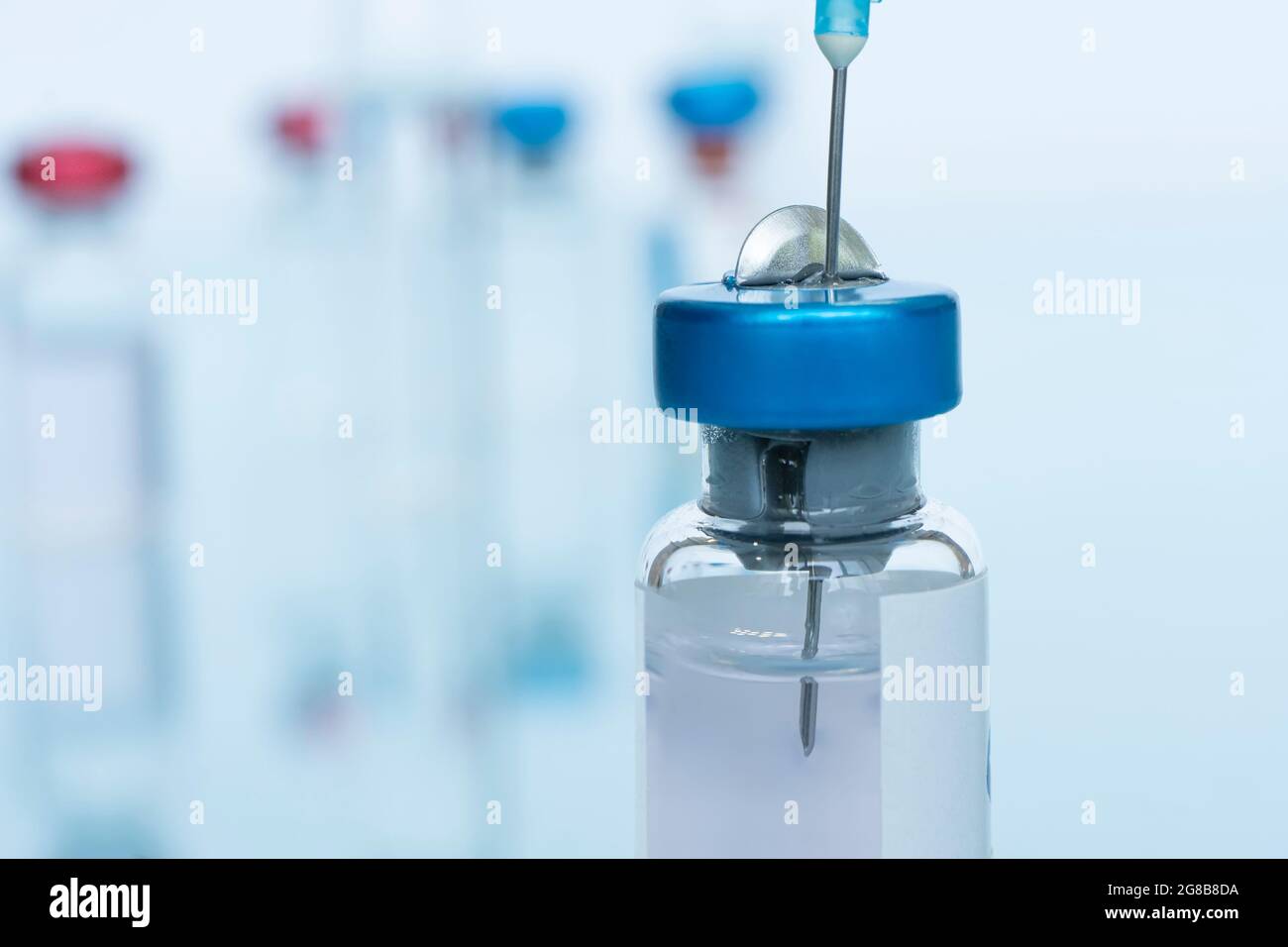 Vaccin en flacon avec seringue percée sur fond bleu Banque D'Images