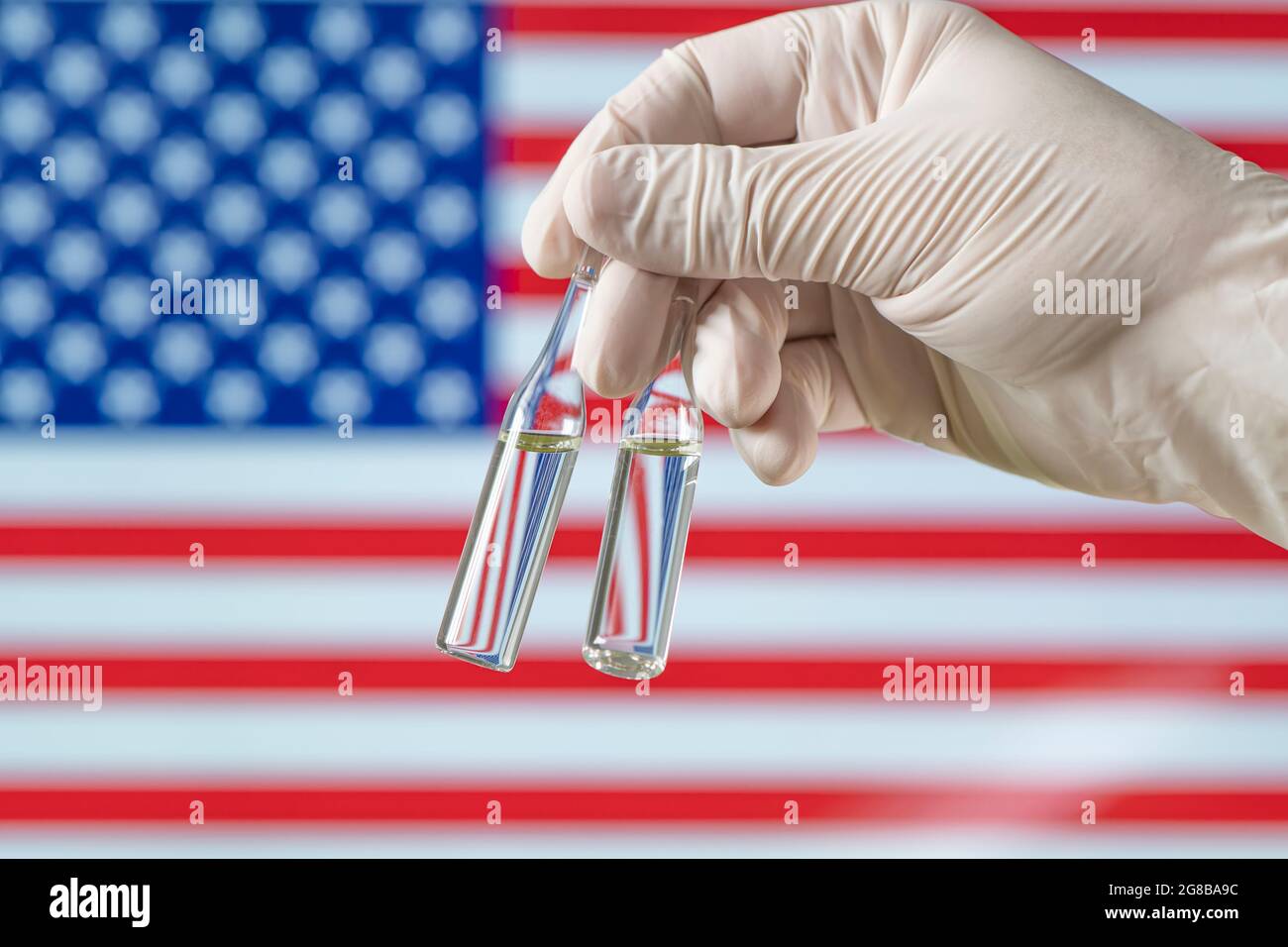 Vaccin COVID-19 sur fond de drapeau américain, flacon avec vaccin américain pour le coronavirus en gros plan. Concept de traitement, essai clinique, distribution et Banque D'Images