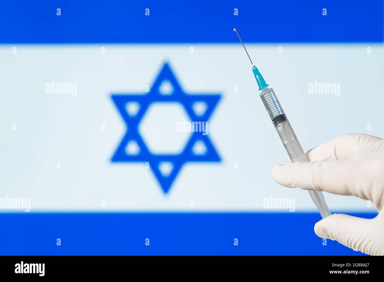 La main du médecin tient une seringue contre le fond du drapeau israélien. Le concept de vaccination de masse contre le coronavirus covid 19 dans le pays Banque D'Images