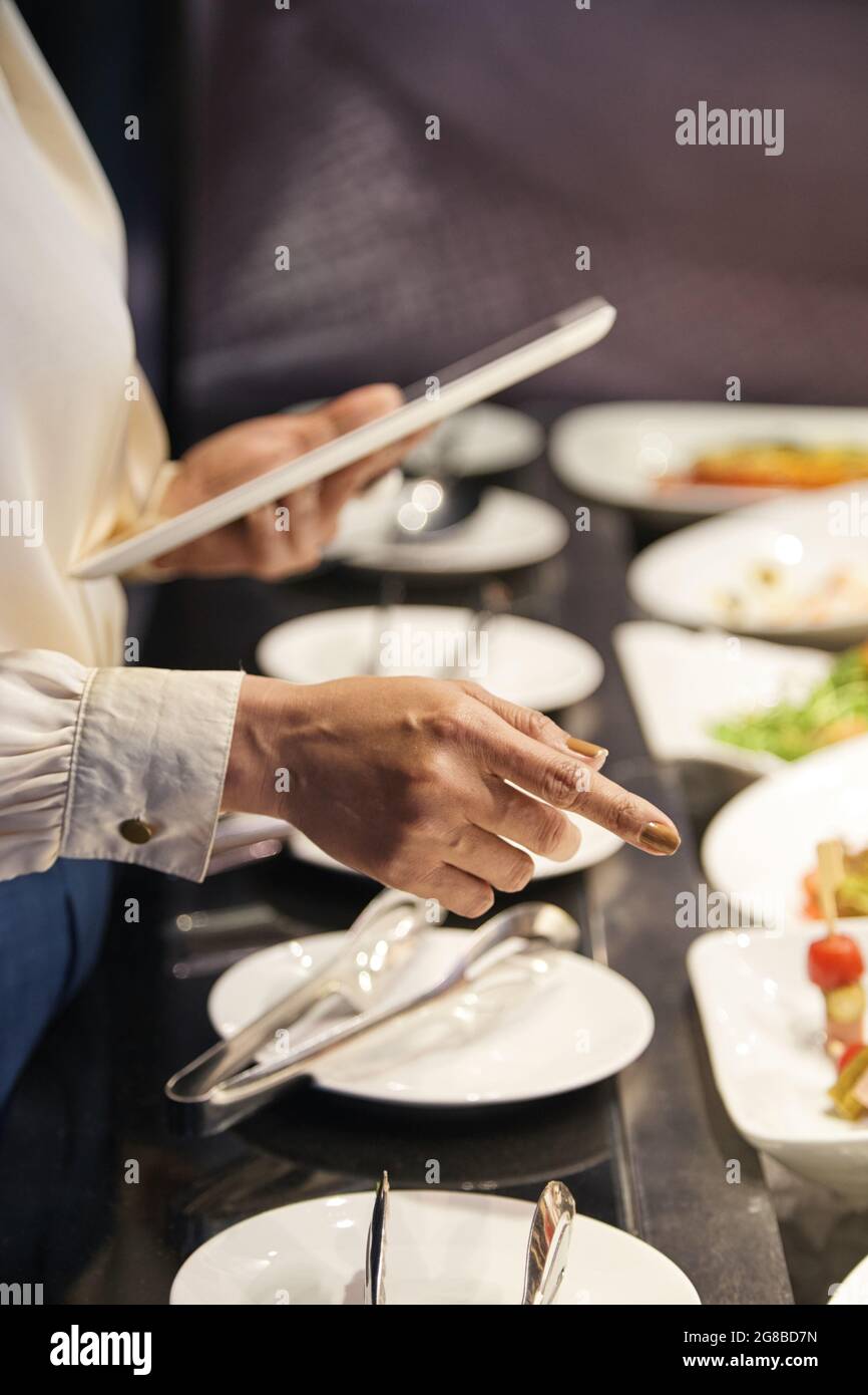Mains du directeur du restaurant avec vérification numérique de la disponibilité des hors-d'œuvre et des salades pour les clients Banque D'Images