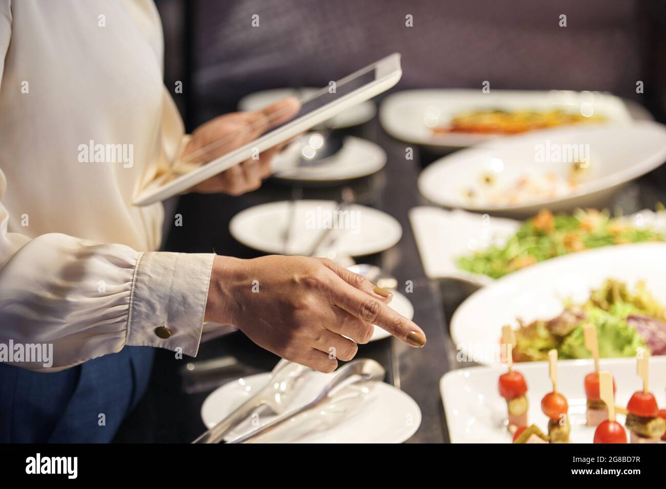 Mains de la femme propriétaire du restaurant vérifiant les assiettes avec les aliments prêts à servir Banque D'Images