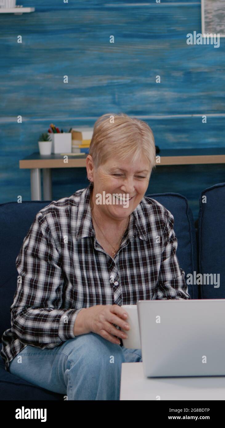 Un couple de personnes âgées ravie au salon avec des neveux sur un ordinateur portable assis sur un canapé. Personne âgée sur Internet en ligne chat technologie vidéo webcam, réunion virtuelle en ligne conférence Banque D'Images