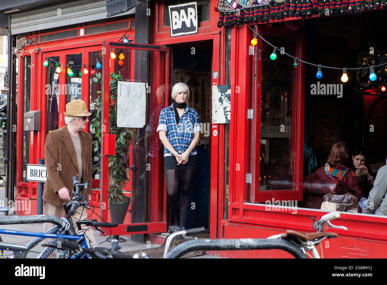 Londres, Royaume-Uni - novembre 2019, UNE fille blonde avec une coupe courte dans une chemise à carreaux et une jupe courte se tient dans la porte du bar, regarde la rade Banque D'Images