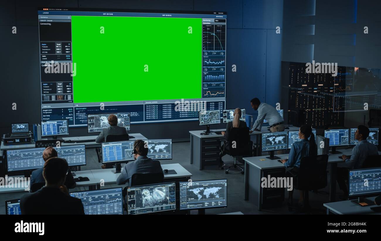 Maquette horizontale sur grand écran vert dans une salle de centre de contrôle de mission avec Flight Director et d'autres contrôleurs travaillant sur des ordinateurs. Équipe de Banque D'Images