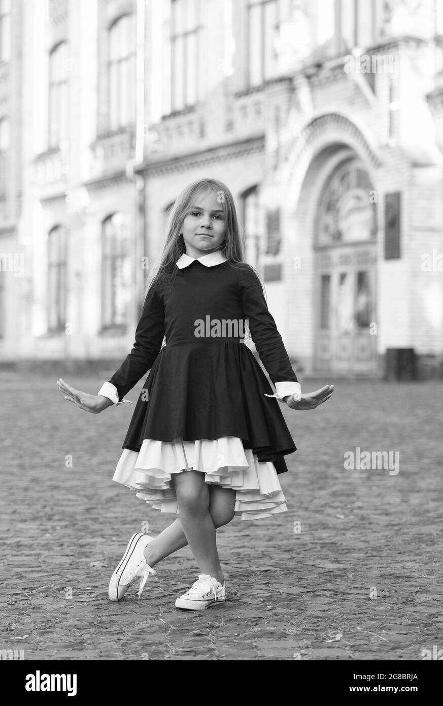 Mignon petite fille de danse dans l'uniforme de l'école faire curtsy dehors, danse Banque D'Images