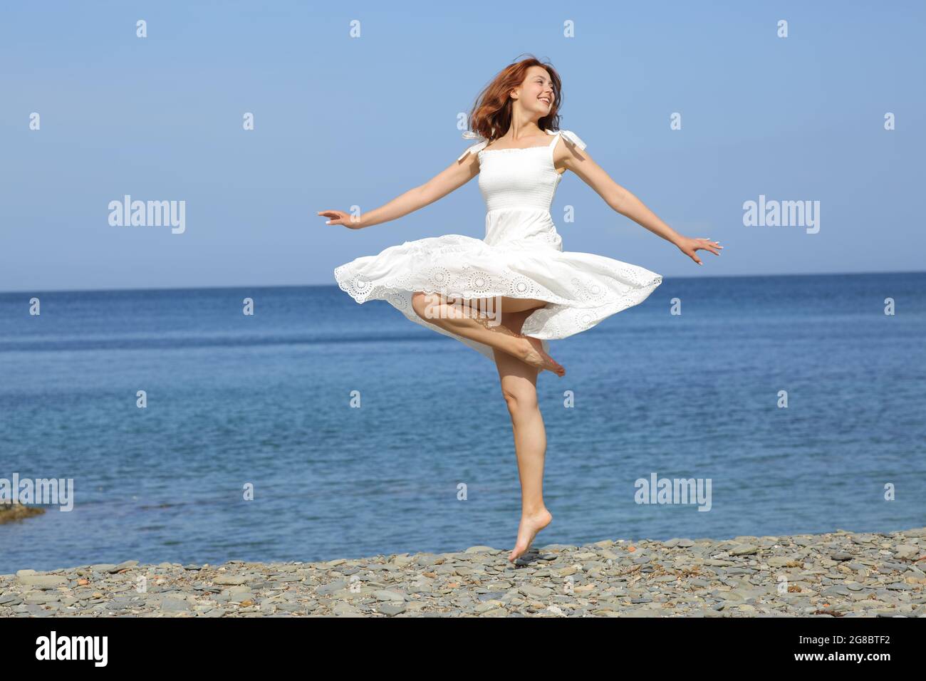 Bonne femme portant une robe blanche en tortillonnage sur la plage Banque D'Images
