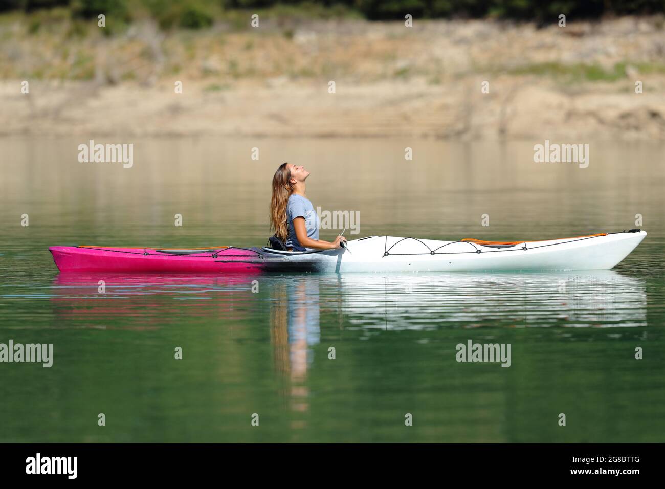 Vue latérale portrait d'une femme se détendant dans un kayak respirant de l'air frais dans un lac Banque D'Images