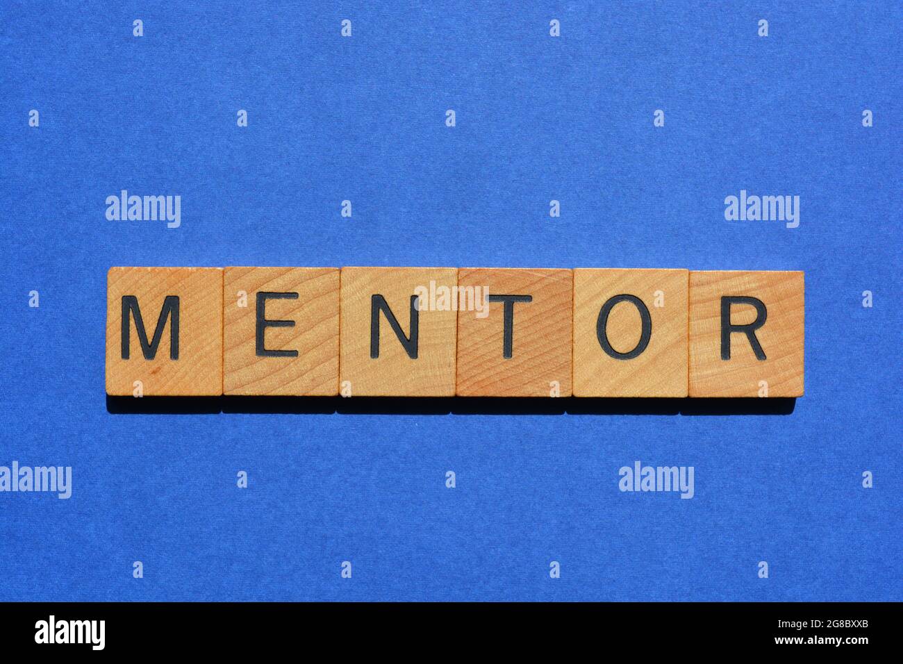 Mentor, mot en lettres de l'alphabet en bois isolées sur fond bleu Banque D'Images