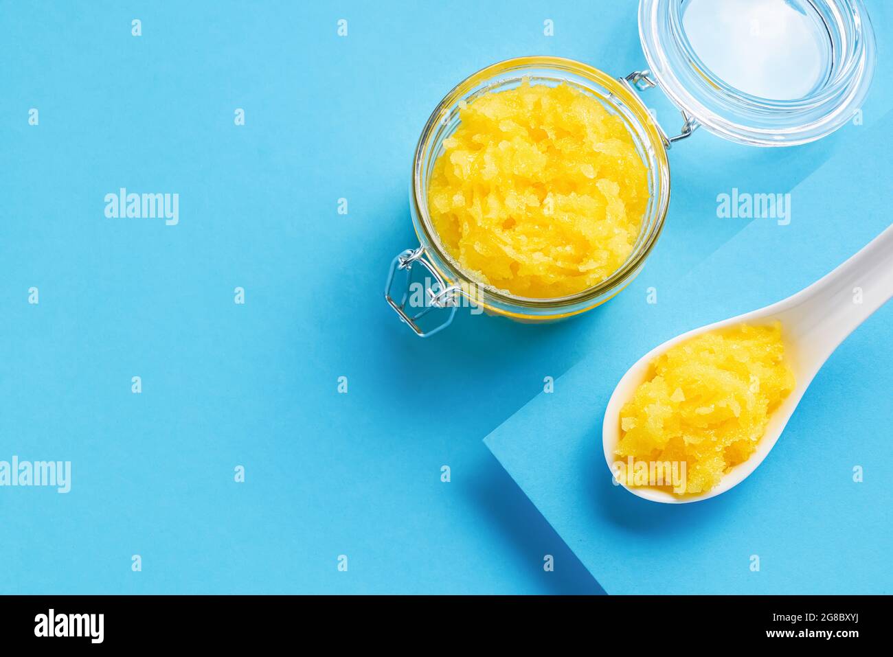 Gommage du corps au citron jaune fait maison dans un pot en verre sur fond bleu. Vue de dessus, espace de copie pour le texte. Concept SPA. Mise au point sélective Banque D'Images