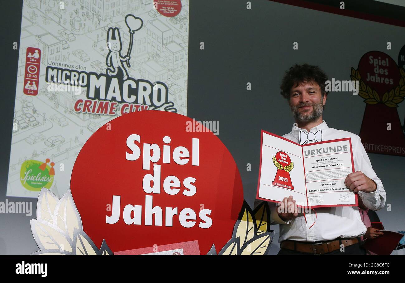 Berlin, Allemagne. 19 juillet 2021. Johannes sich, concepteur de jeux, détient le certificat du gagnant pour le jeu de l'année 2021. Son jeu, 'Mitro Macro crime City' a été choisi par un jury comme jeu de l'année. Une grande affiche noire et blanche et quelques cartes sont tous les joueurs ont besoin de résoudre des dizaines de meurtres et de morts en utilisant la carte de style objet caché de la ville. Le jeu est publié par Pegasus Spiele-Verlag et coûte 25 euros. Credit: Wolfgang Kumm/dpa/Alay Live News Banque D'Images