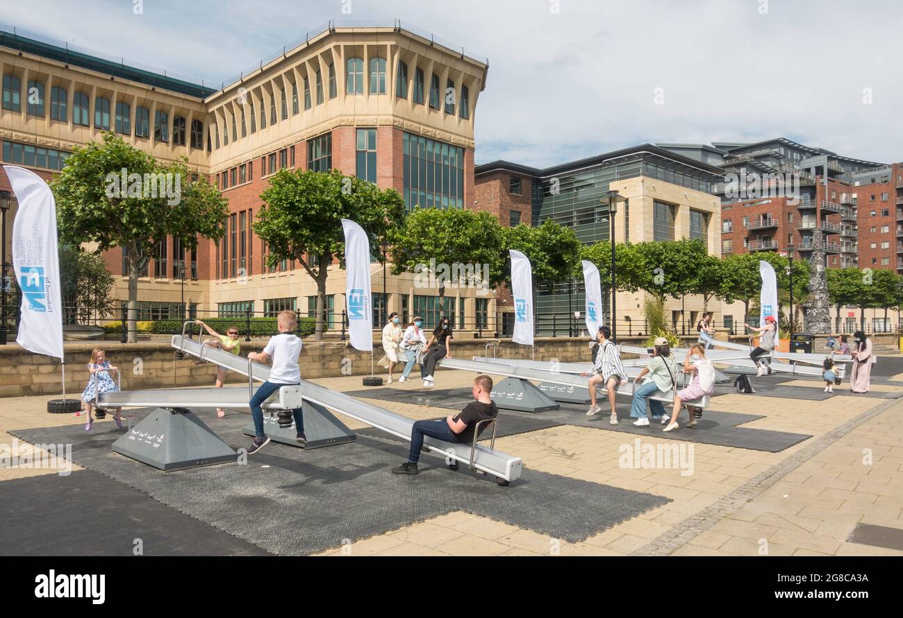 L'été dans la ville, les personnes jouant sur les seesaws dans le 'Wave Field' sur Newcastle upon Tyne Quayside, Angleterre, Royaume-Uni Banque D'Images