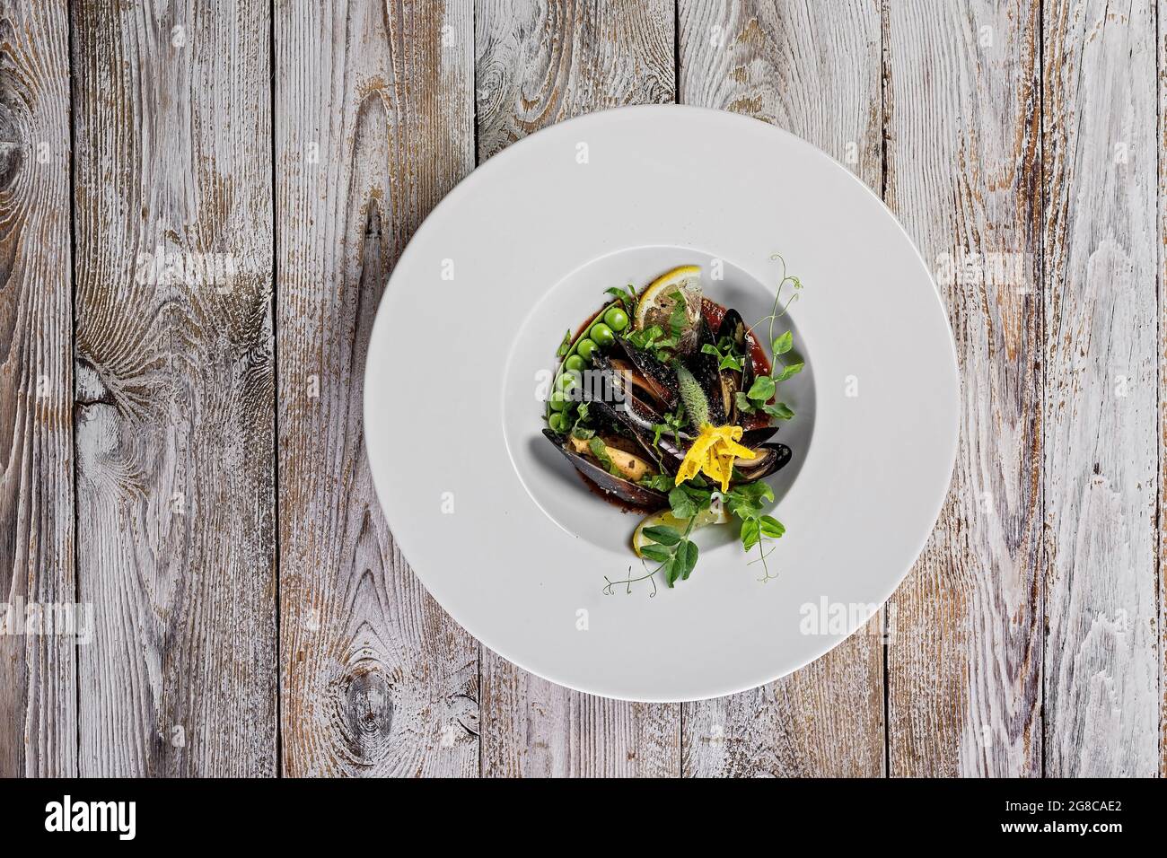 Vue de dessus moules avec légumes et sauce au vin sur une assiette blanche. Fruits de mer méditerranéens traditionnels sains et délicieux. Recette de restaurant. Arrondi wh Banque D'Images