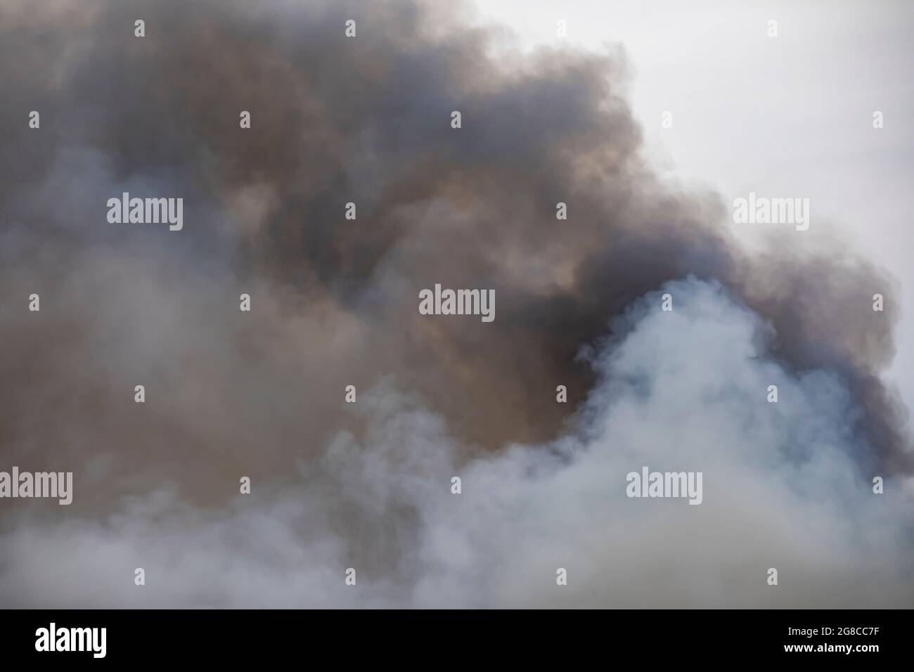 Fumée tourbillonnante d'un grand feu, semblable aux nuages. Nuages Cumulus. Banque D'Images