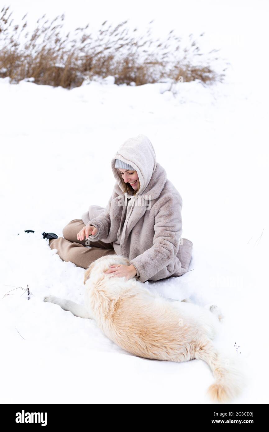 Jeune belle femme et son chien d'or retriever s'amuser en hiver. Banque D'Images