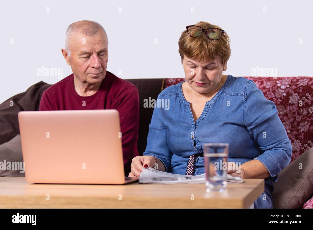 Un couple âgé se rendant dans son entreprise, une femme lisant un journal et un homme ouvrait un ordinateur portable et s'asseyant près de sa femme. Banque D'Images