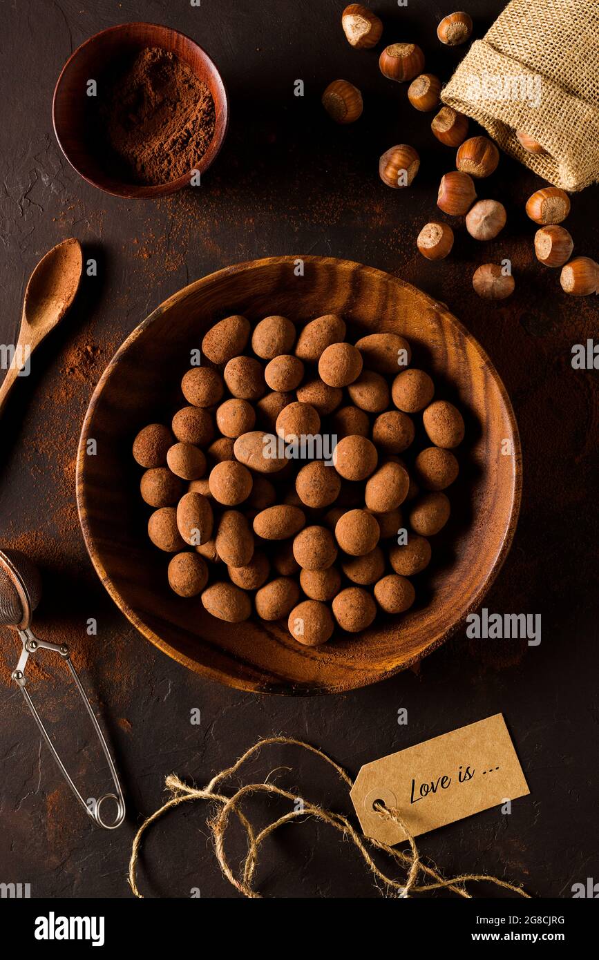 Chocolats dans un bol en bois sur fond rustique foncé Banque D'Images