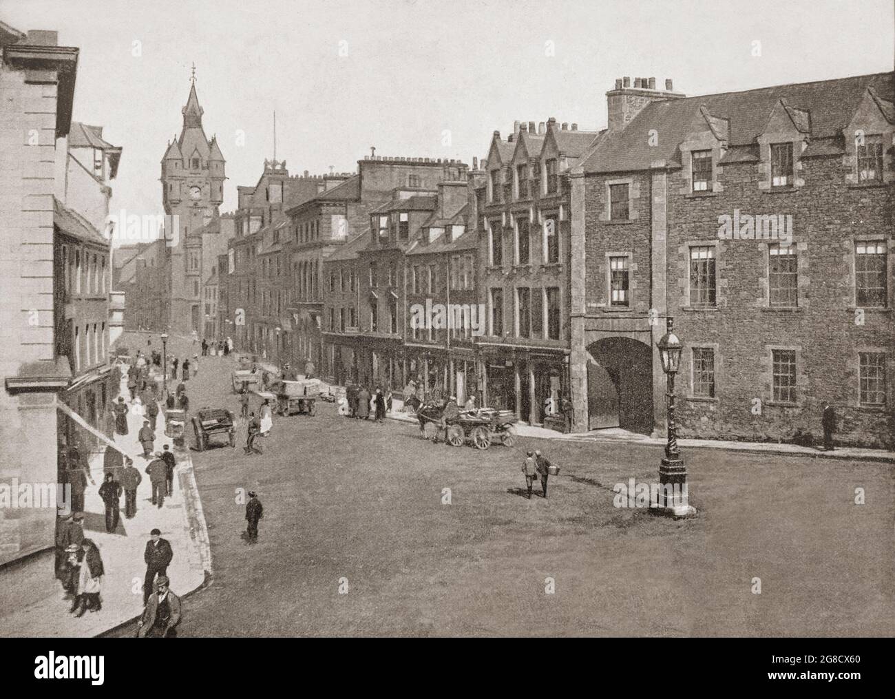 Vue de la fin du XIXe siècle sur High Street à Hawick, ville aux frontières écossaises et comté historique de Roxburghshire, dans l'est du sud des Uplands. L'hôtel de ville de style écossais-baronial de Hawick est visible au bout de la rue, ainsi que ses nombreux bâtiments en grès avec toits en ardoise. Banque D'Images