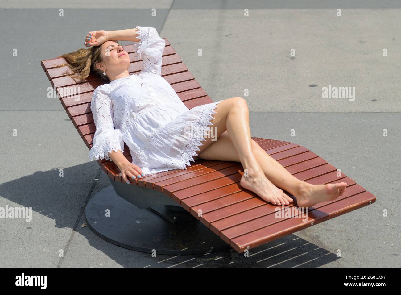 Femme profitant d'une journée de détente en prenant un bain de soleil sur un fauteuil inclinable dans la chaleur estivale Banque D'Images