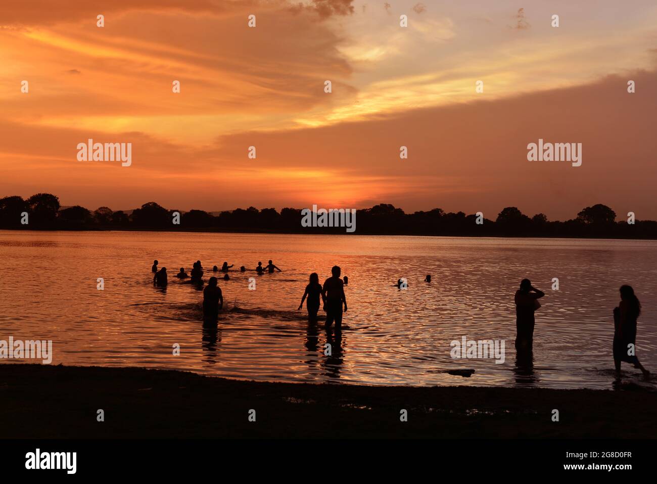 Silhouette de pèlerins prenant un bain rituel dans la rivière au coucher du soleil. Sri Lanka, Asie Banque D'Images