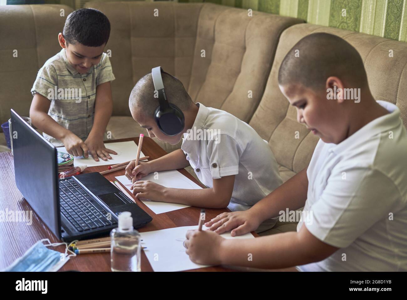 Des élèves de sexe masculin dessinant tout en écoutant la classe d'art en ligne sur un ordinateur portable à la maison Banque D'Images