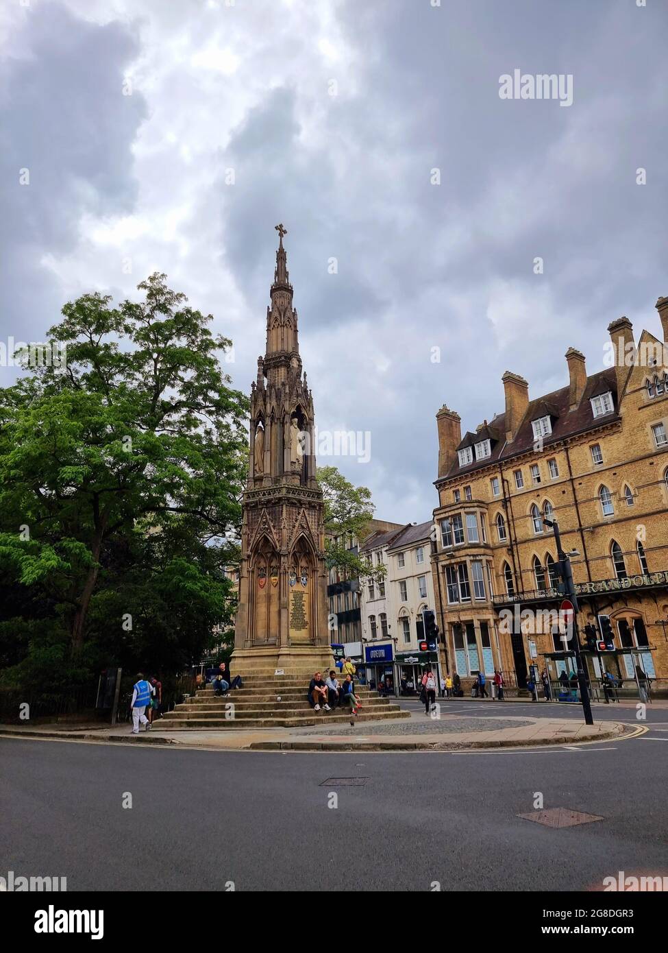 Les touristes et les étudiants s'assoient et se détendent sur les marches du Mémorial des martyrs, un monument en pierre situé à l'intersection de St Giles, de la rue Magdalen et de la rue Beaumont, à l'ouest du Balliol College, Oxford, Angleterre. Il commémore les Martyrs d'Oxford du XVIe siècle. Conçu par George Gilbert Scott, le monument a été achevé en 1843 après deux ans de travail, après avoir remplacé « une vieille maison pittoresque mais chancelante ». Royaume-Uni. Banque D'Images