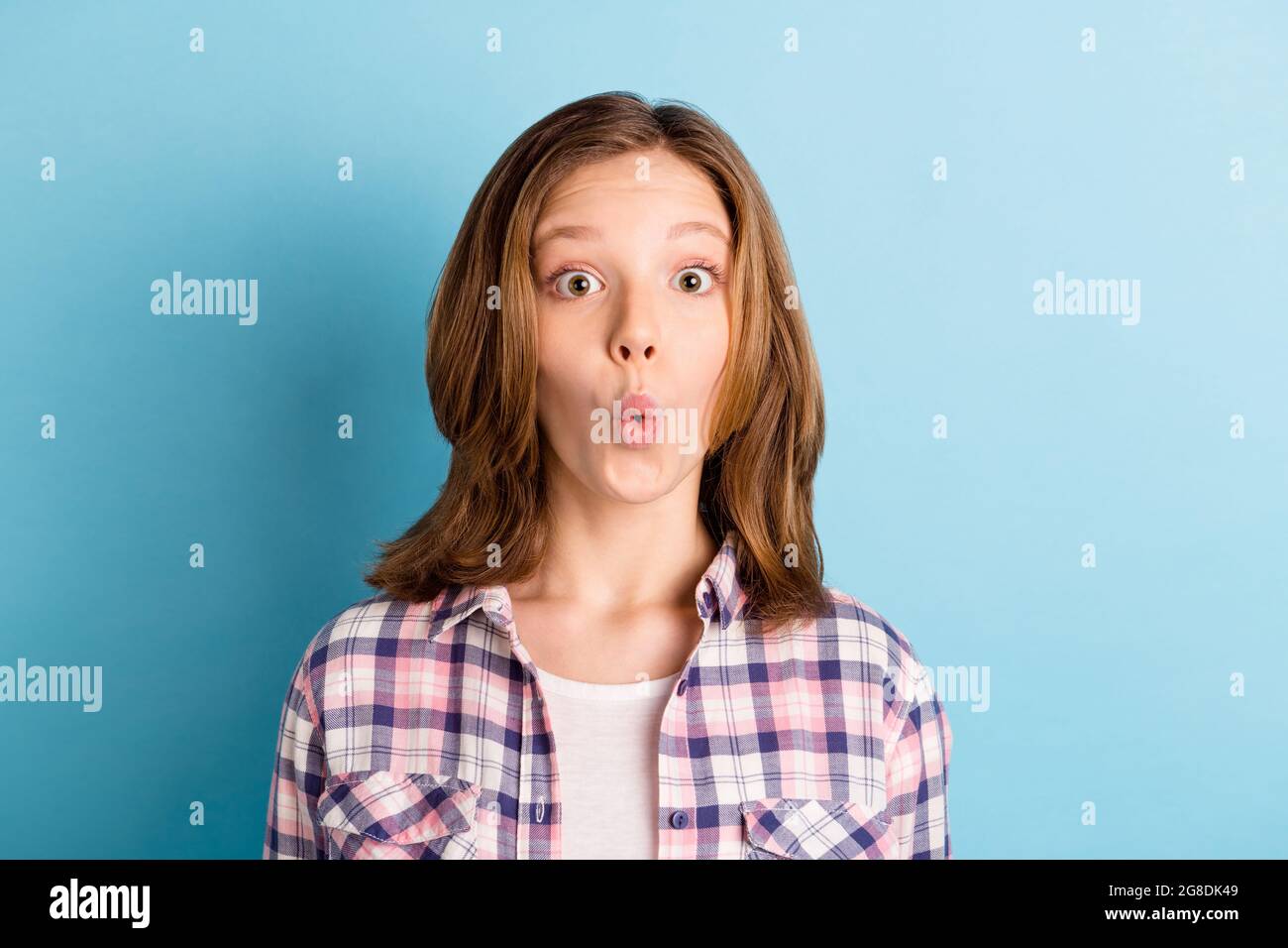 Photo de l'école de charme choqué fille port chemise à carreaux grands yeux isolé couleur bleu fond Banque D'Images