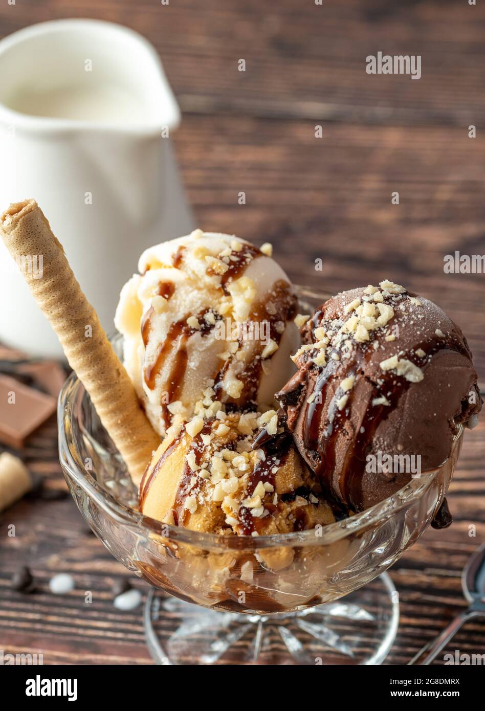 Glace Roma au chocolat, à la crème et au caramel dans un bol en verre avec une sauce au chocolat et aux noisettes. Banque D'Images