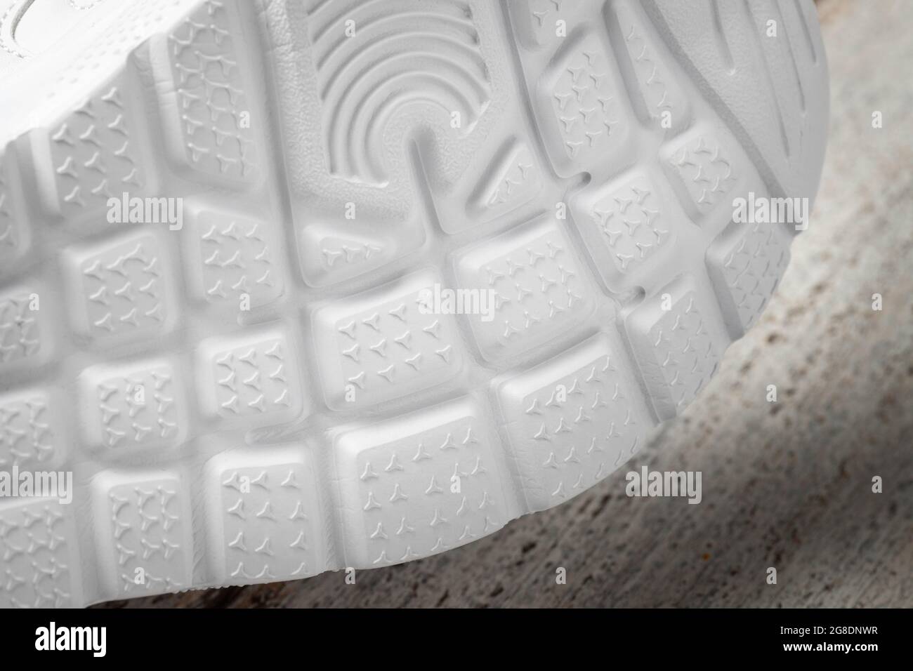 Macro photographie des semelles des sneakers blanches. Baskets de sport pour enfants couchés sur le côté avec semelle antidérapante en caoutchouc blanc sur un bois Banque D'Images