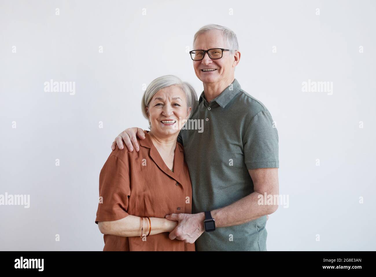 Portrait à la taille d'un couple senior heureux qui s'embrasse et regarde l'appareil photo tout en se tenant sur un arrière-plan blanc, espace de copie Banque D'Images